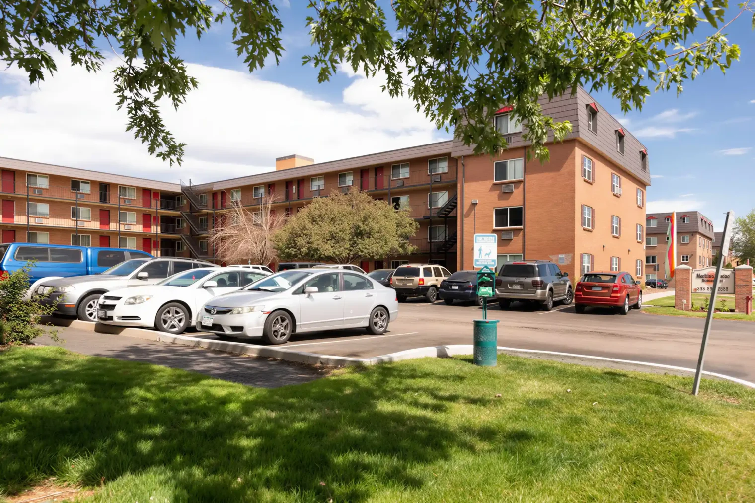 Exterior view of Meridian Garden Apartments with resident parking and landscaped grounds in Denver, CO