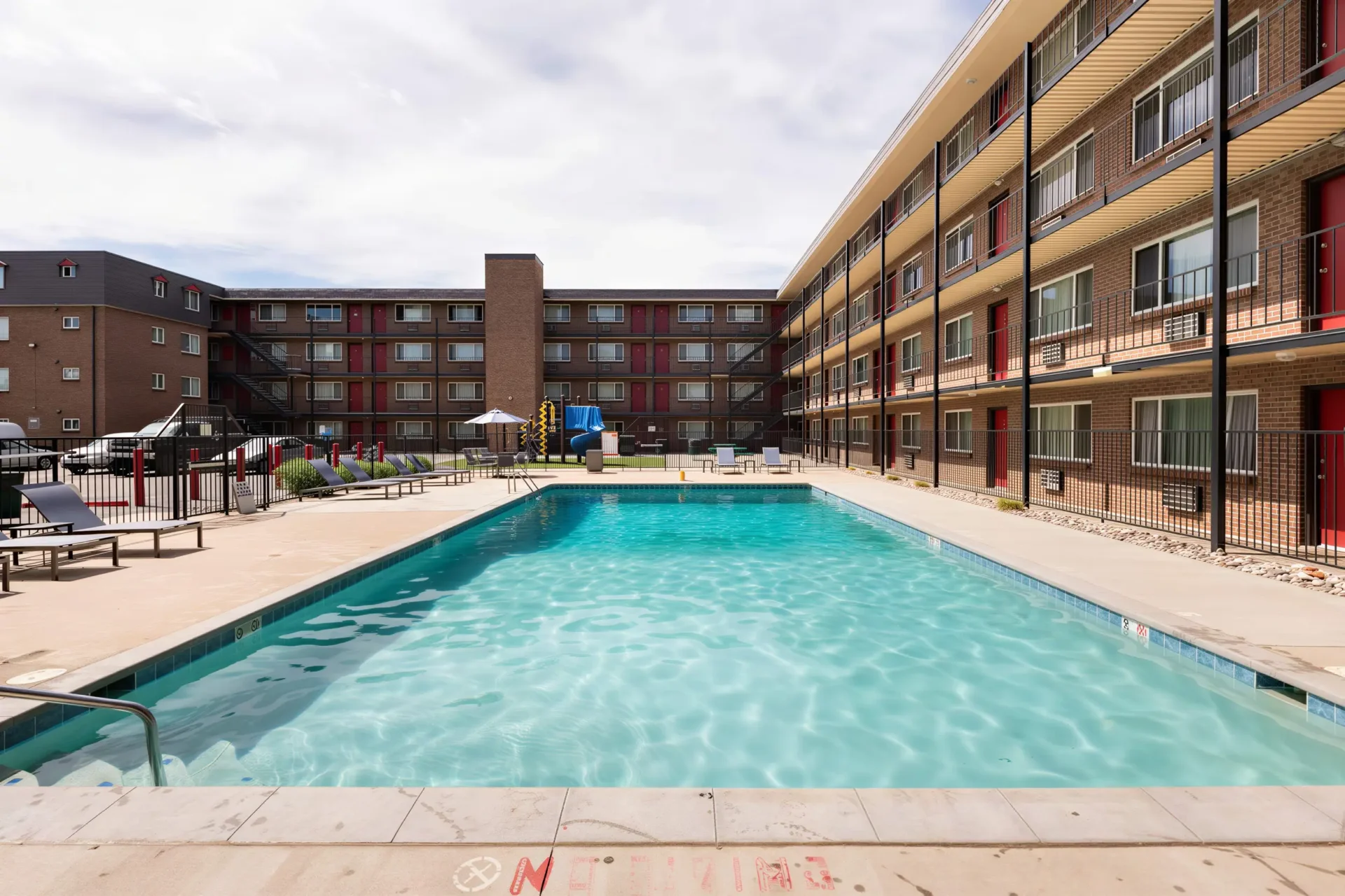 Heated swimming pool with lounge seating in the courtyard at Meridian Garden Apartments in Denver